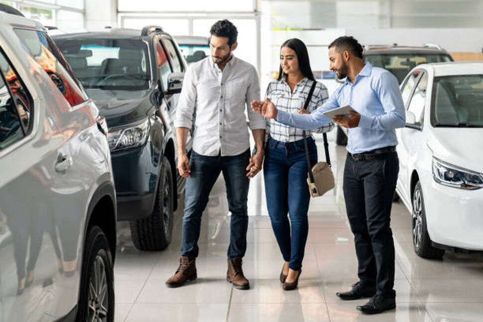 Couple working with a salesperson at an automotive dealership